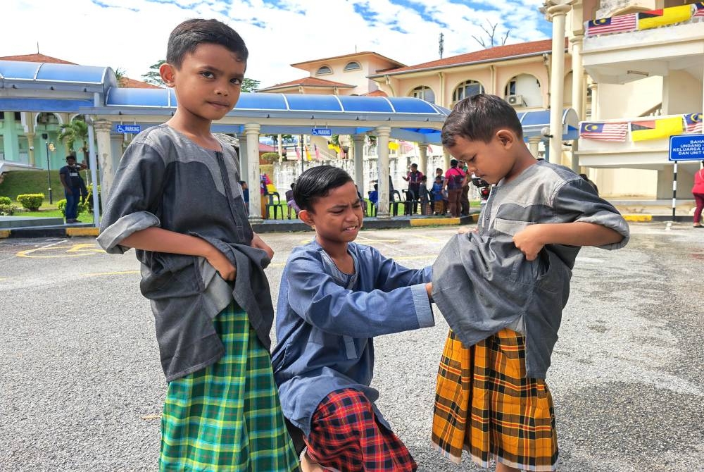 Muammad Afiq Habbibn (tengah) membetulkan kain pelikat adiknya, Muhamad Adib Habb