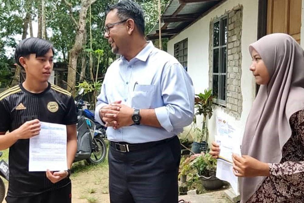 Hail Hilman (tengah) bersama Muhammad Omar Mokhtar (kiri) dan Salmah di Kampung Budi, Pokok Sena pada Isnin.