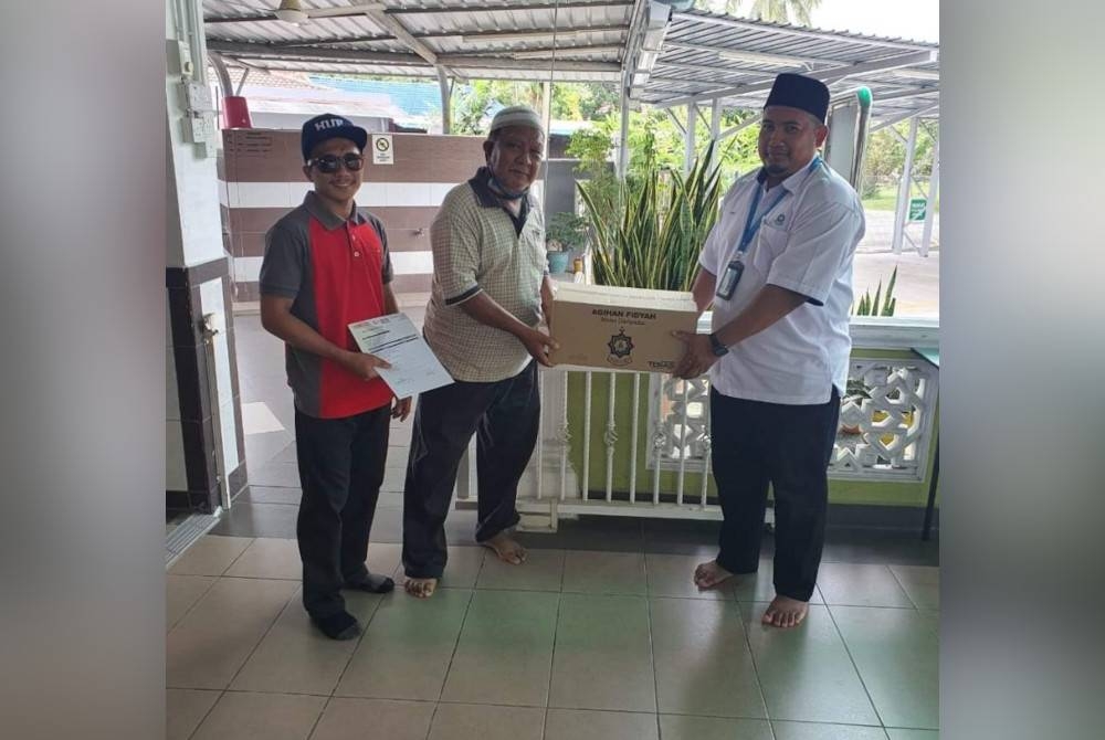 Wakil MAIS (kanan) menyerahkan bantuan fidyah berupa set makanan kering di beberapa kawasan di Hulu Selangor dan Hulu Langat.