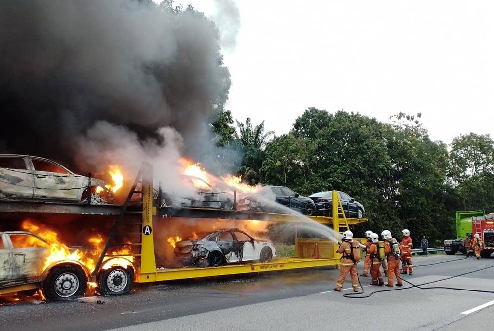 Bomba memadam kebakaran treler yang membawa muatan kereta Honda di Kilometer 227.2 Lebuh Raya Utara Selatan (arah Utara), dekat Pedas pada Selasa. - Foto Ihsan polis