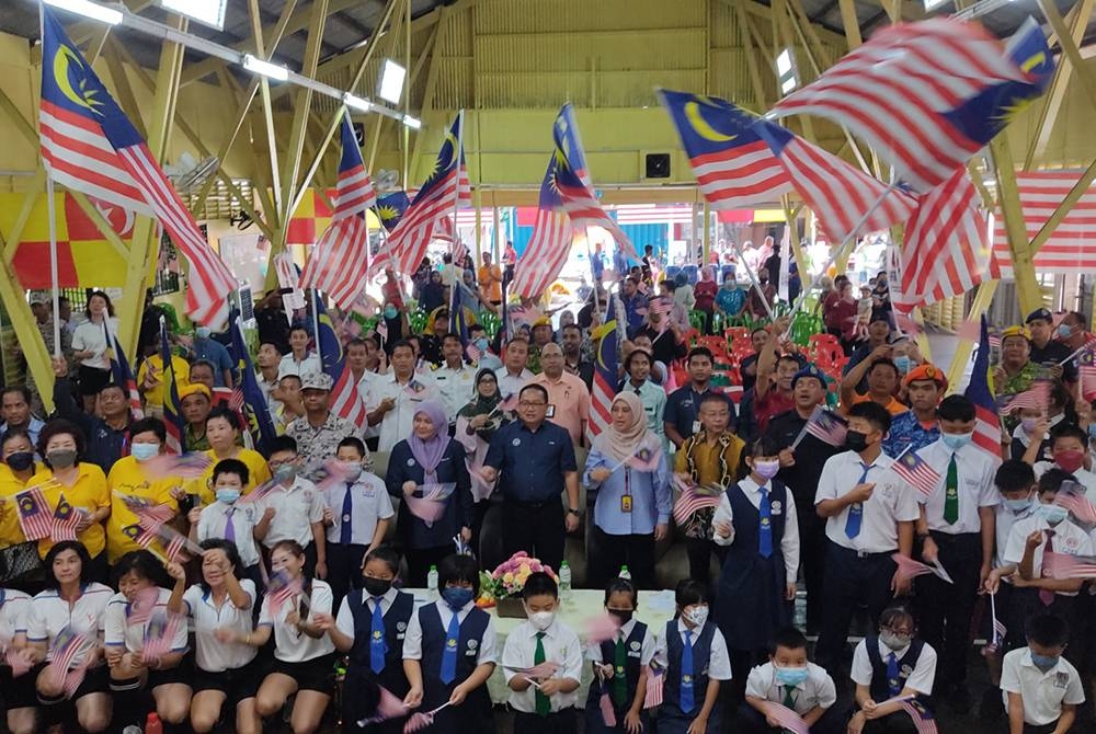 Zamri (tengah, baris kedua) bersama penduduk Pulau Ketam, di sini mengibarkan Jalur Gemilang dalam program Semarak Hari Malaysia Bersama Komuniti Pulau Ketam, di sini.