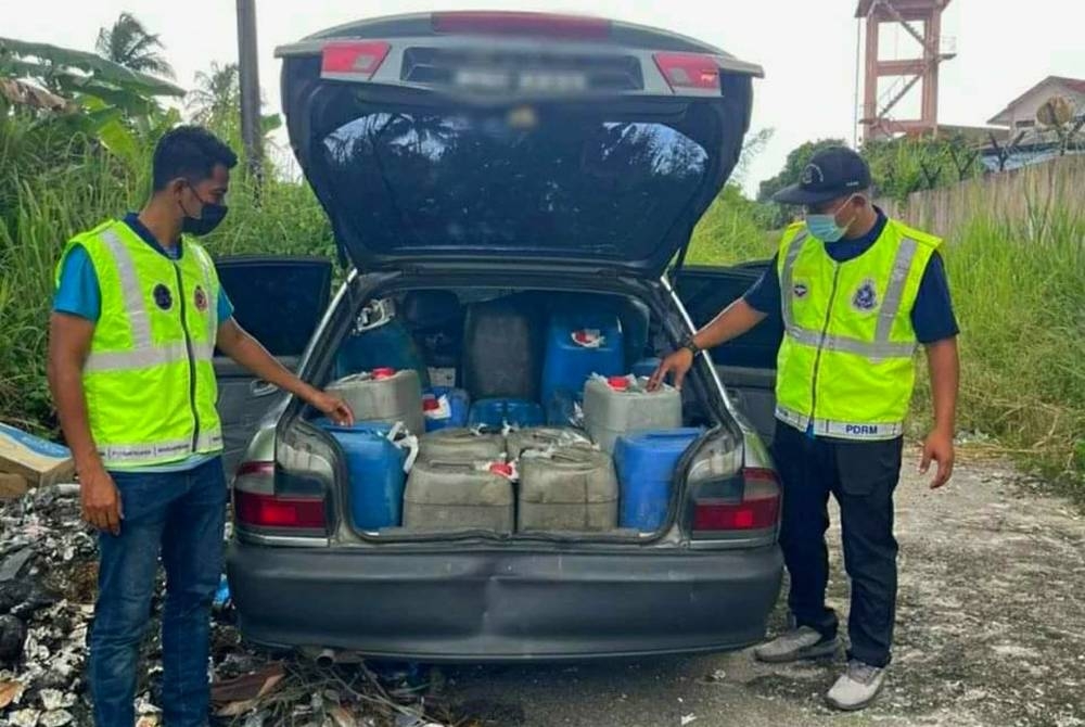 Anggota KPDNHEP Kelantan menunjukkan minyak diesel yang berjaya dirampas di Bunut Susu, Pasir Mas pada Rabu.