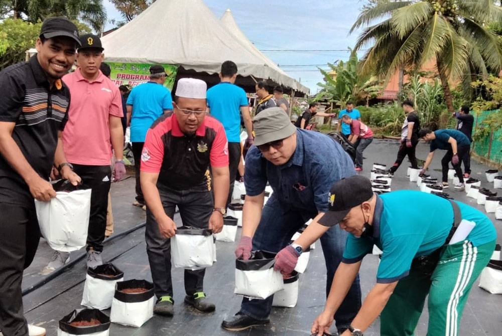 Rosnazli ( dua dari kanan) bergotong-royong mengangkut plastik tanaman untuk menanam pelbagai sayuran pada Program Local Agenda 21, Program Kebun Kejiranan/Komuniti di Pangsapuri Bandar Baru Kubang Kerian pada Sabtu.