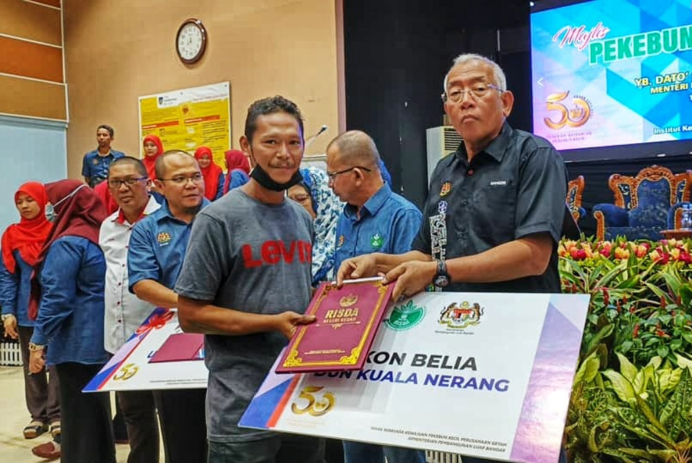 Mahdzir (dua dari kanan) menyerahkan replika cek kepada salah seorang ikon belia di program Pekebun Kecil Makmur RISDA peringkat Kedah di sini pada Ahad.