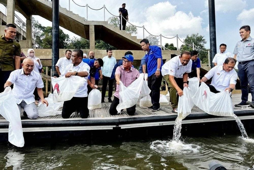 Abdullah (kanan) menyaksikan Menteri Besar Pahang, Datuk Seri Wan Rosdy Wan Ismail (depan, tengah) dan Menteri Tenaga dan Sumber Asli, Datuk Seri Takiyuddin Hassan (dua dari kiri) melepaskan benih ikan di Tasik Chini, pada Sabtu.