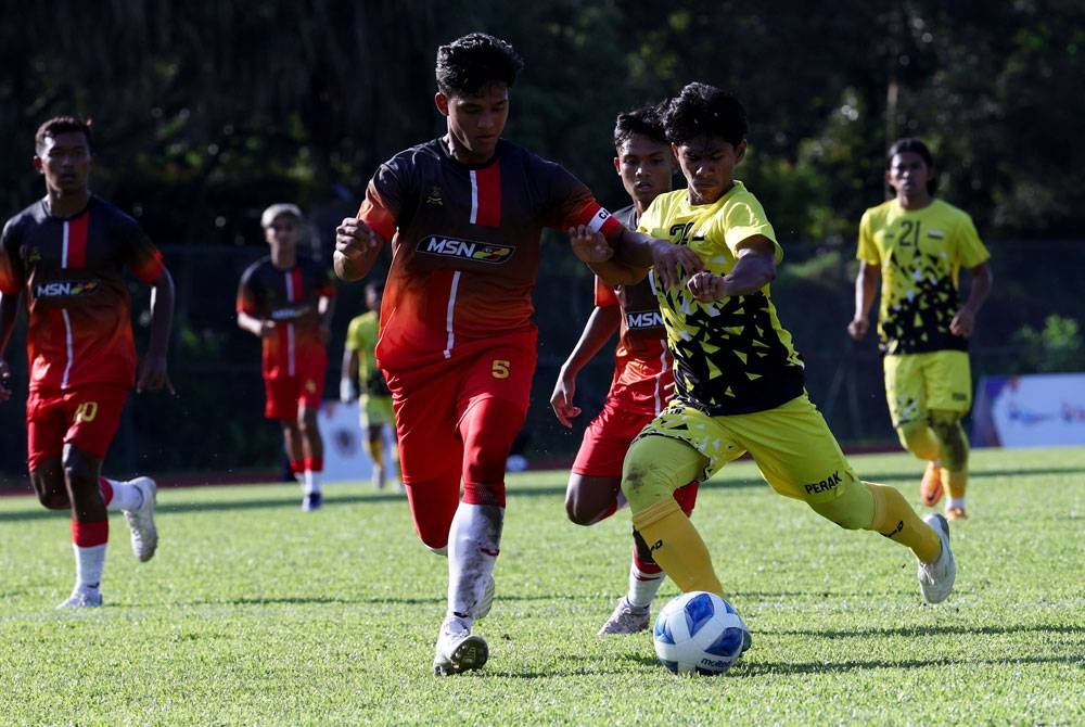 Pemain Selangor Akmal Izzuddin Azlan mengasak pemain Perak dalam perlawanan pertama acara Bola Sepak Sukan Malaysia (Sukma) di UM Arena, pada Isnin. - Foto Bernama