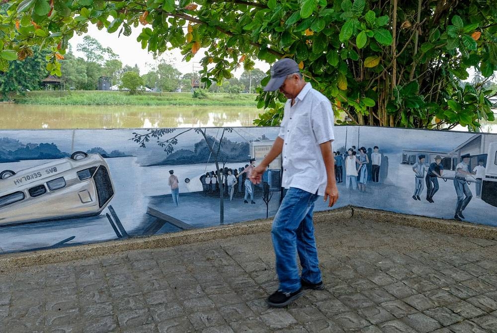 Seorang penduduk setempat melintasi mural yang dilukis bagi memperingati tragedi feri karam yang mengorbankan 27 mangsa pada 13 September 1972 di Sungai Kerian pada Selasa. - Foto Bernama