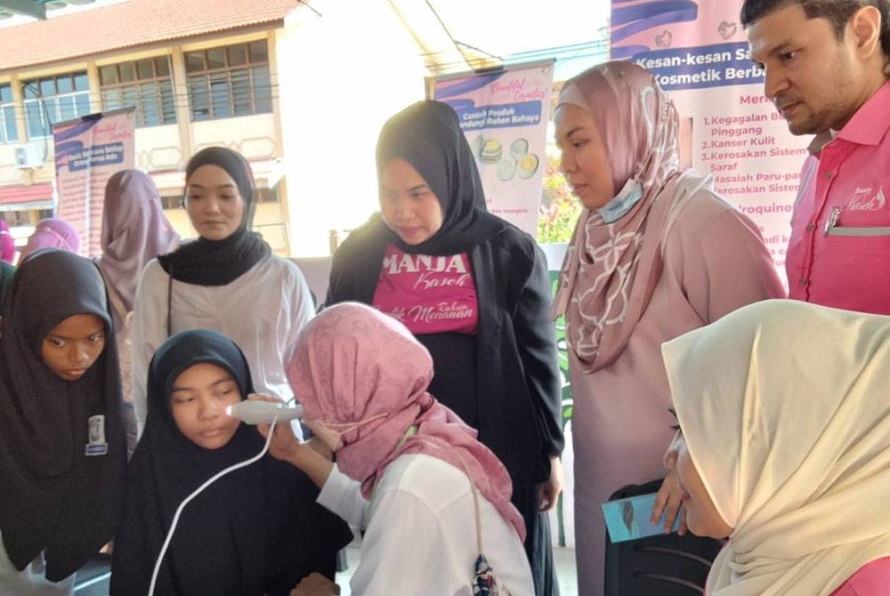 Dr Siti Fatimah Noor (dua dari kanan) dan Mohd Faizul melihat kakitangan Beauty Qaseh memeriksa wajah pelajar Kempen Keselamatan Kosmetik di sebuah sekolah pada Rabu.