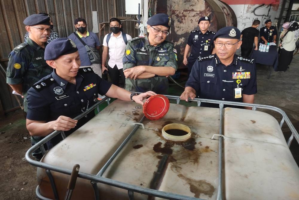 Arjunaidi (kanan) menunjukkan antara rampasan yang dibuat polis dalam serbuan gudang pemindahan diesel bersubsidi di Jalan Klang - Banting, Kuala Langat, pada Rabu.