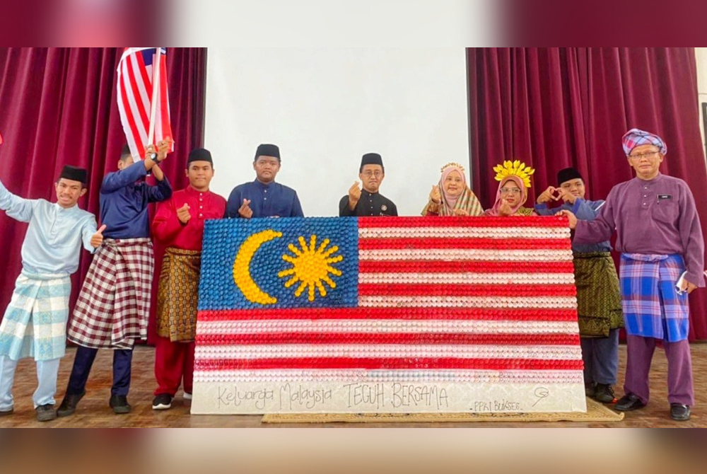 Guru terlibat merakam gambar bersama Jalur Gemilang yang dihasilkan pelajar PPKI menggunakan 2,200 penutup botol terpakai.