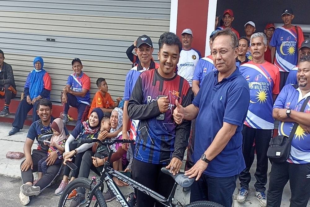 Hasni (kanan) menyampaikan hadiah cabutan bertuah sempena program Benut Fun Walk, Hari Tanpa Kenderaan di Pekan Benut pada Jumaat.