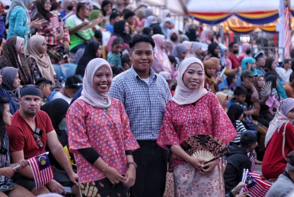 Muhammad Nur Aiman (tengah) bersama dua sahabatnya yang turut mengenakan pakaian tradisional 50-an pada program Sambutan Hari Malaysia 2022 di Dataran Memorial Pengisytiharan Kemerdekaan Banda Hilir pada Sabtu.