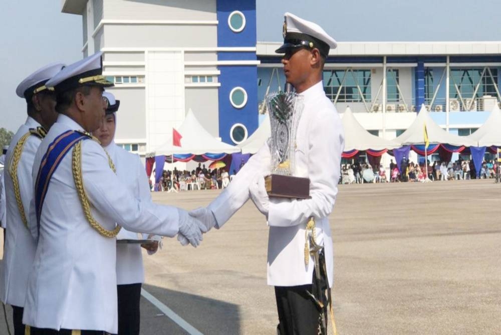 Saiful Lizan (kiri) menyampaikan anugerah terbaik keseluruhan kepada Laskar Kelas II Maritim Abdullah Mohd Nazri ketika menyempurnakan perbarisan tamat latihan Laskar Kelas II Maritim Siri 16/2021 Maritim Malaysia di Padang Kawat Pusat Latihan dan Akademi Maritim Sultan Ahmad Shah (Amsas) di Gebeng, pada Sabtu.