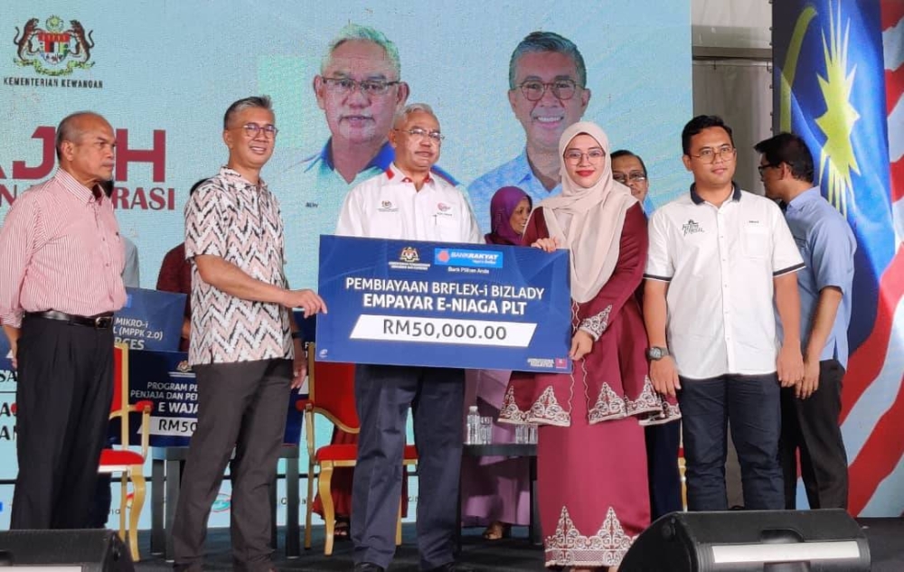 Tengku Zafrul (dua dari kiri) sambil diiringi Menteri KUSKOP, Tan Sri Noh Omar (tiga dari kiri) menyampaikan geran pembiayaan sewa beli komersial kepada salah seorang penerima pada Program Jelajah KUSKOP Negeri Selangor di Pekarangan Terminal Bas Kuala Selangor pada Sabtu.