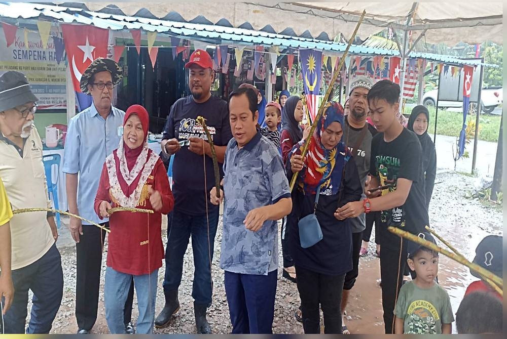 Ahmad ( tengah) mencuba sukan rakyat pada Karnival Sukan Peladang sempena Hari Malaysia di Kampung Parit Baru Ayer Baloi pada Ahad.