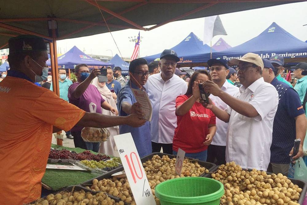 Abd Rahim menunjukkan penggunaan transaksi tanpa tunai kepada pengguna di Pasar Tani UTC di sini pada Ahad.