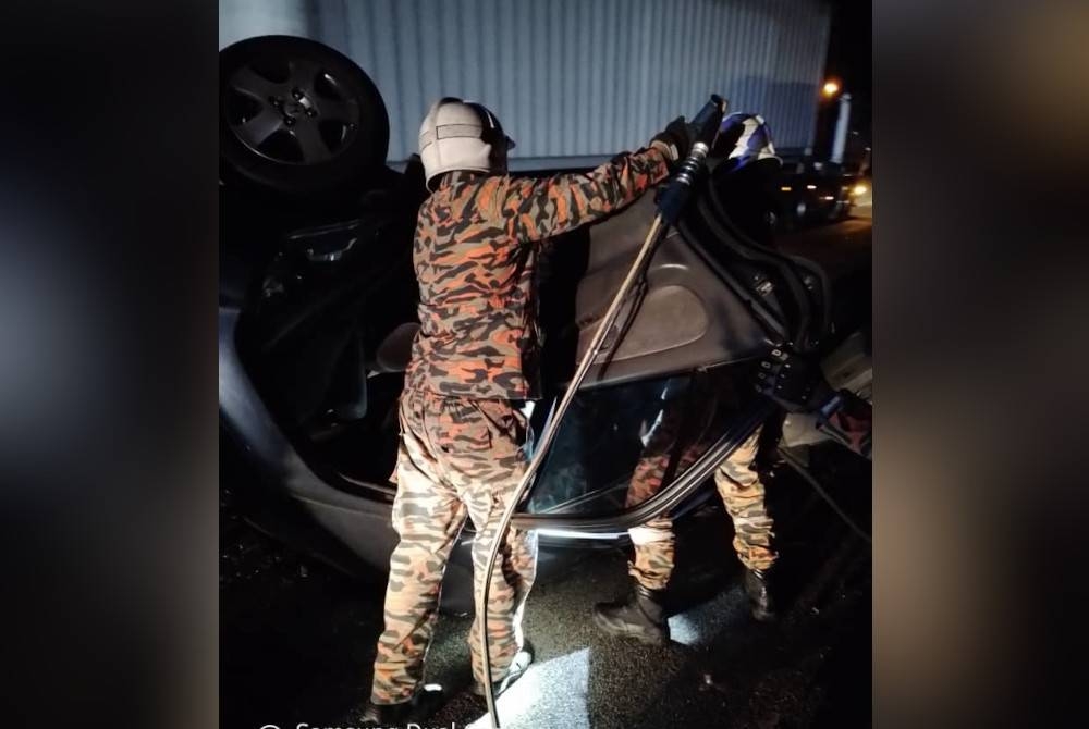 Anggota bomba mengeluarkan mangsa yang tersepit selepas kereta dipandu terbabas dan terbalik di Kilometer 86.6 Lebuhraya Utara-Selatan, arah utara, Ayer Hitam, Kluang pada Isnin. - Foto ihsan JPBM Johor