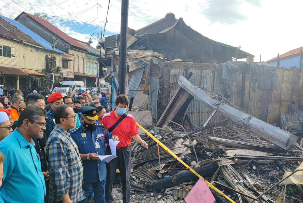 Ahmad Samsuri (dua dari kiri) melihat deretan 12 rumah kedai di Kampung Cina di sini, yang hangus dalam kebakaran pada malam Ahad.