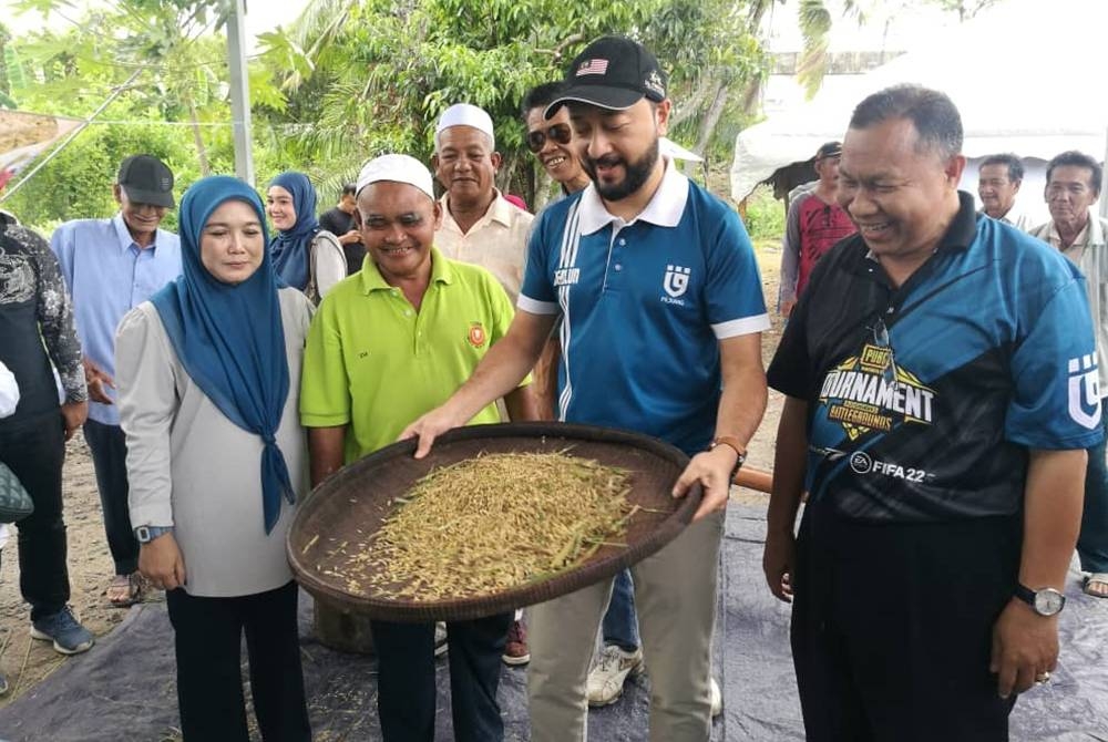 Mukhriz (dua dari kanan) menampi padi secara tradisional menggunakan nyiru sebelum proses membuat emping ketika program ‘Jom Mengemping bersama Ahli Parlimen Jerlun’ di Megat Dewa di sini pada Jumaat.