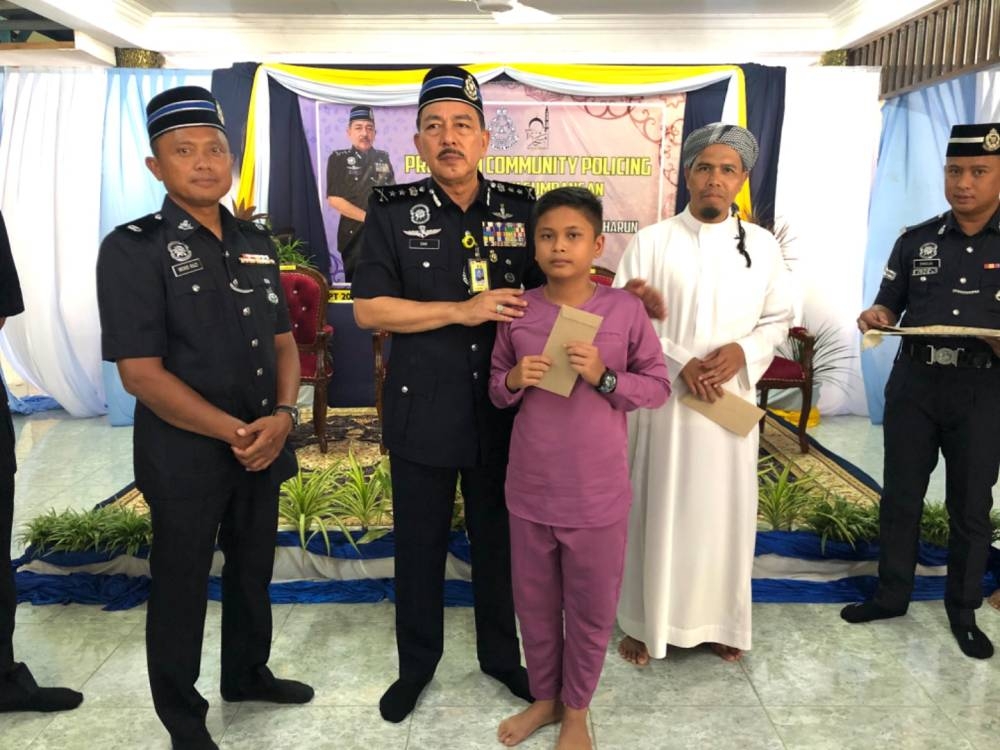 Muhamad Zaki (dua, kiri) menyampaikan sumbangan kepada penerima Mohamad Syahir Zafran Mohd Shaharil, 13, (tiga, kiri). 