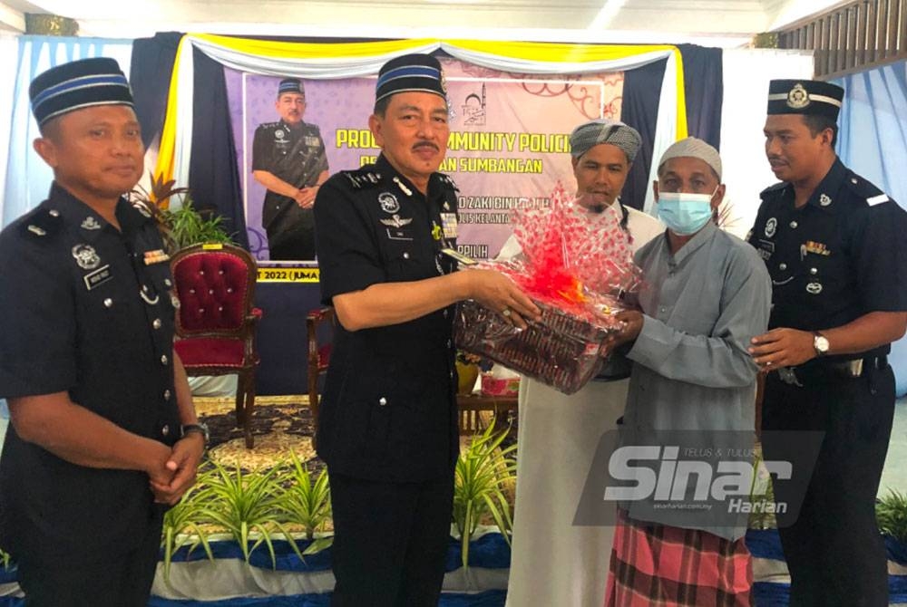 Muhamad Zaki (dua dari kiri) menyampaikan sumbangan kepada penerima Mohamad Zahari Che Embun di Masjid As-Syakirin, Kelewek, Tanah Merah.