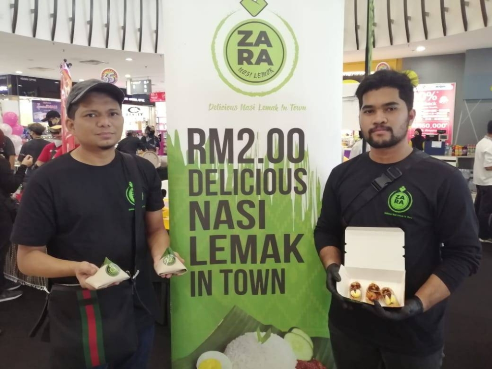 Mohd Shauqi (kiri) bersama nasi lemak bungkus dan sushi nasi lemak yang merupakan menu utama di restorannya.