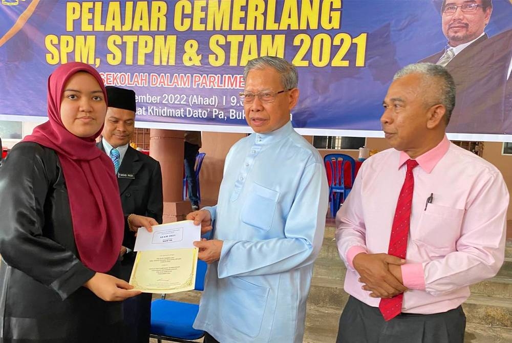 Mustapa (dua dari kanan) menyampaikan sumbangan kepada salah seorang penerima pada Majlis Penyampaian Sumbangan Pelajar Cemerlang SPM, STPM & STAM 2021 di Jeli pada Ahad.