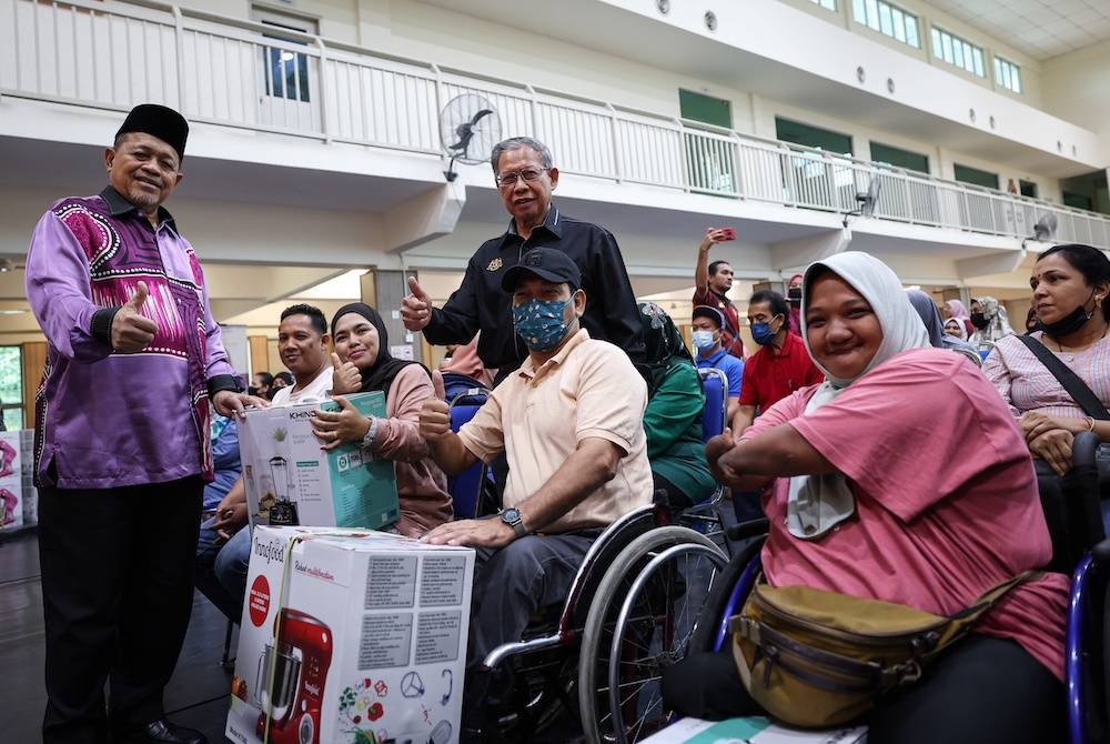 Shahidan (berdiri, kiri) bersama Mustapa (berdiri, kanan) menyerahkan sumbangan peralatan dapur kepada penerima Zarina Abu Safian dari Perumahan Awam Desa Rejang (kanan) bersama Azman Hassan (dua dari kanan) dari PPR Kerinci pada Program Pembasmian Kemiskinan Tegar Keluarga Malaysia di Kompleks Komuniti Muhibbah PPR Kampung Muhibbah Bukit Jalil pada Ahad. -Foto:Bernama