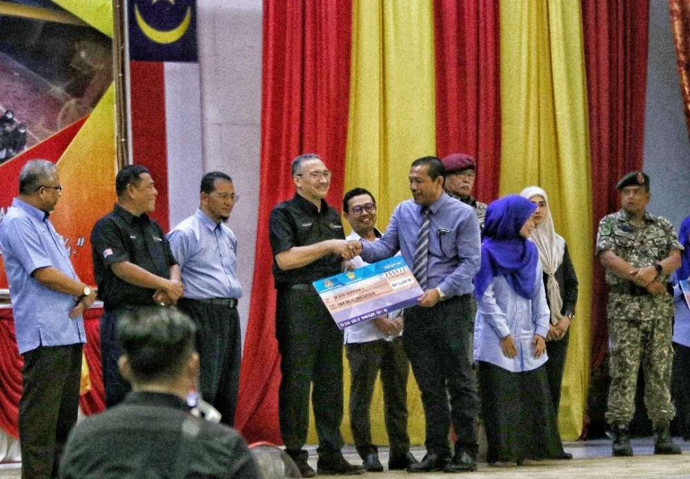 
Hishammuddin (empat dari kiri) menyampaikan replika cek sumbangan RM15,000 kepada Guru Besar Sekolah Kebangsaan (SK) Terendak 1, di Sungai Udang pada Rabu.