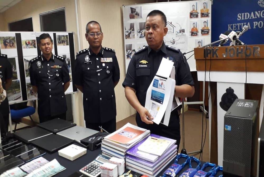 Kamarul Zaman menunjukkan buku dan dokumen yang mengandungi butiran senarai peminjam along pada sidang akhbar di IPK Johor, Johor Bahru pada Khamis