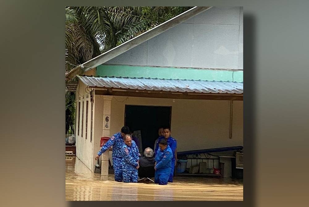 Anggota APM Johor, membawa keluar seorang mangsa banjir di Kampung Sri Gambut, Pontian pada Ahad. Foto APM Johor