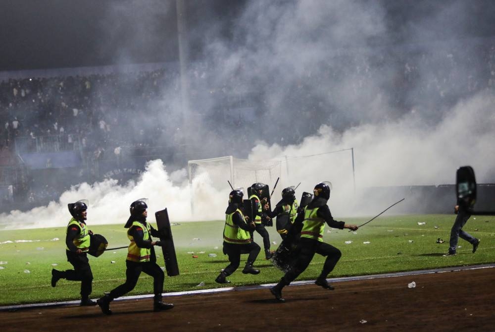 Anggota polis berlari untuk menghalang peminat bola sepak memasuki padang semasa pertembungan antara peminat di Stadium Kanjuruhan di Malang, Jawa Timur, Indonesia pada Sabtu. - Foto EPA