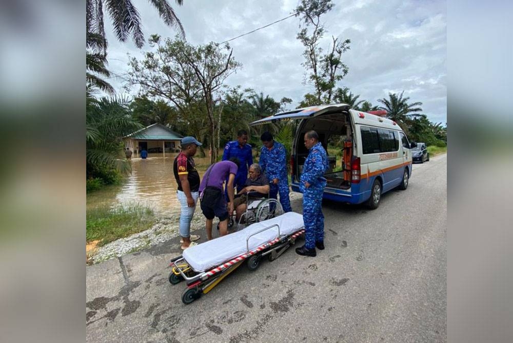 Anggota APM memindahkan mangsa banjir di Pontian ke PPS di SK Melayu Raya, Pontian, pada Ahad, selepas kediaman penduduk dilanda banjir kilat.