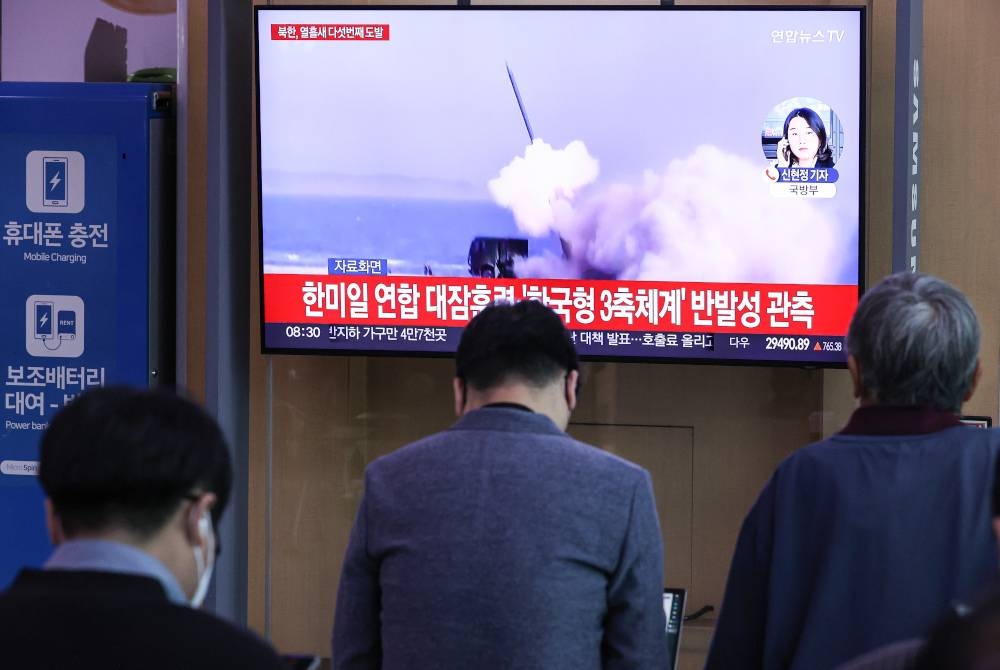 Orang ramai menonton laporan TV mengenai pelancaran peluru berpandu balistik jarak perantaraan (IRBM) Korea Utara ke lautan Pasifik melepasi Jepun pada Selasa. - Foto EPA