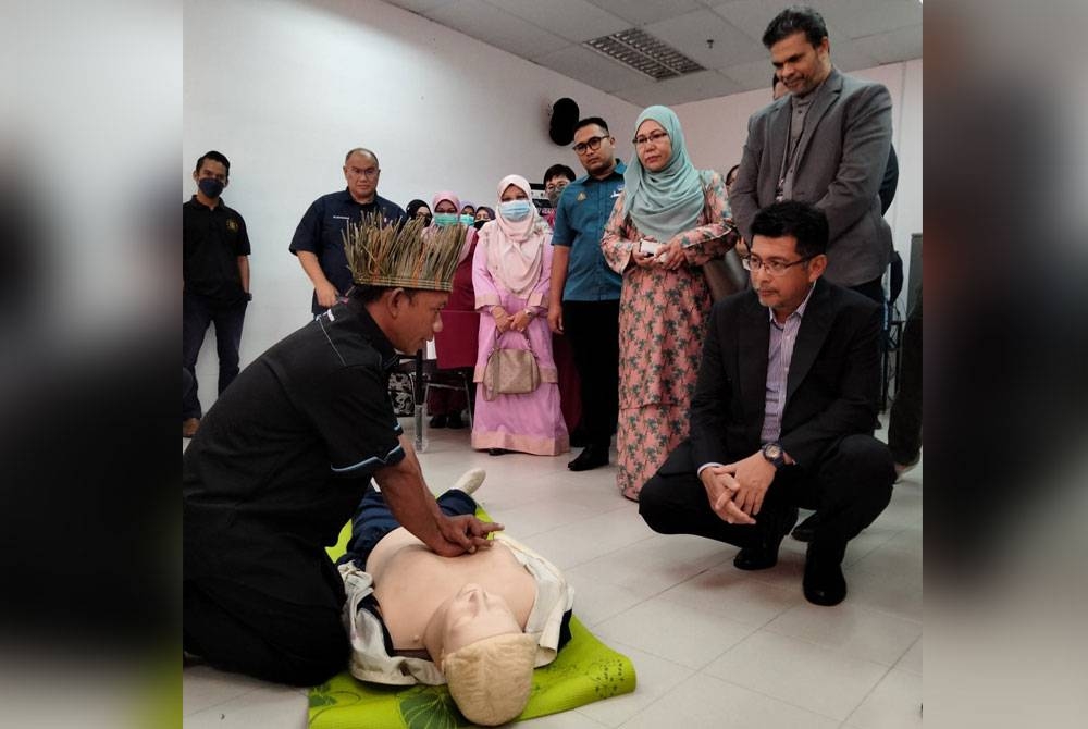 Dr Nik Hisamuddin (kiri), Dr Shaik Farid (berdiri, kiri) dan Roslina (berdiri, dua dari kiri) melihat sukarelawan Orang Asli, Arizan Long, 39, menunjukkan cara memberi pertolongan cemas kepada mangsa lemas.