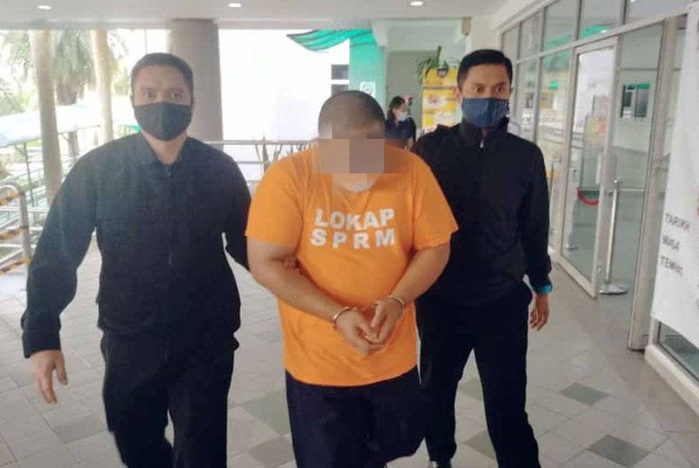 Anggota SPRM membawa suspek (tengah) ke Mahkamah Majistret Shah Alam untuk permohonan reman berhubung kes rasuah pada Selasa.