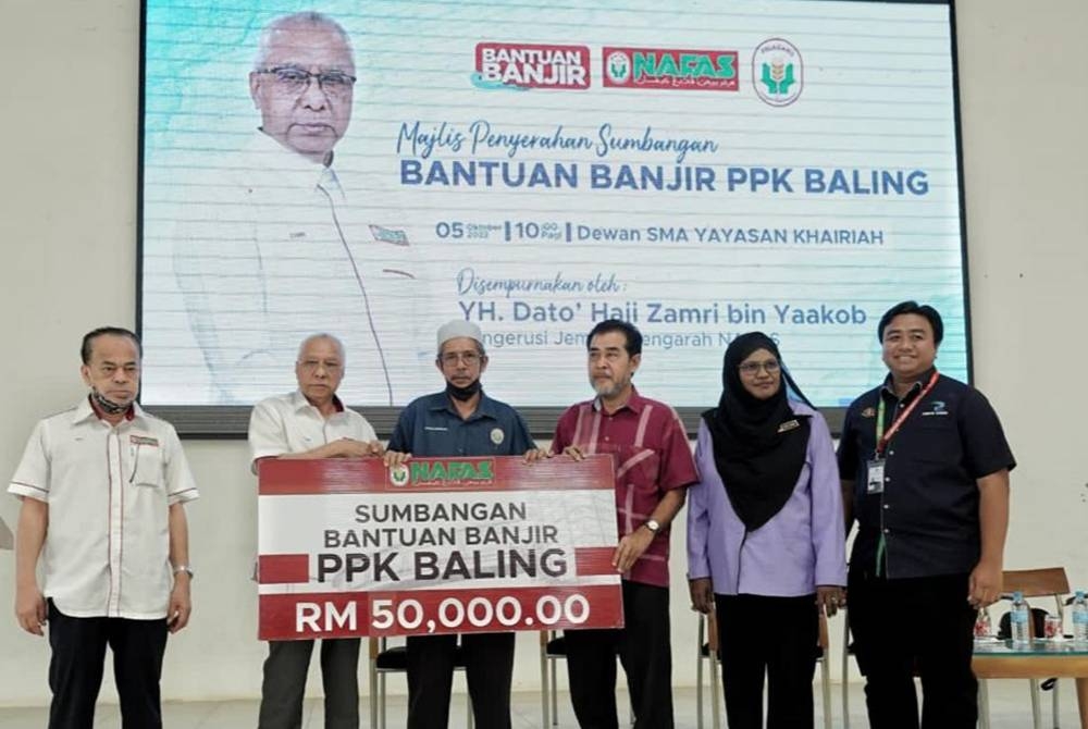 Zamri (dua dari kiri) menyerahkan replika cek berjumlah RM50,000 kepada wakil PPK Baling untuk diagihkan secara berperingkat kepada mangsa yang terjejas banjir di Baling Julai lalu.