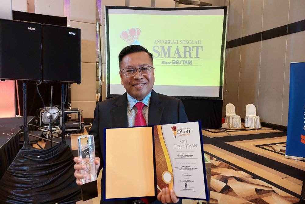 Mohd Nizam Saidin menunjukkan piala dan sijil penyertaan selepas memenangi Anugerah Sekolah S.M.A.R.T Sinar Bestari 2021/2022 (ASSSB) kategori Sekolah Rendah Bandar di Shah Alam pada Rabu.