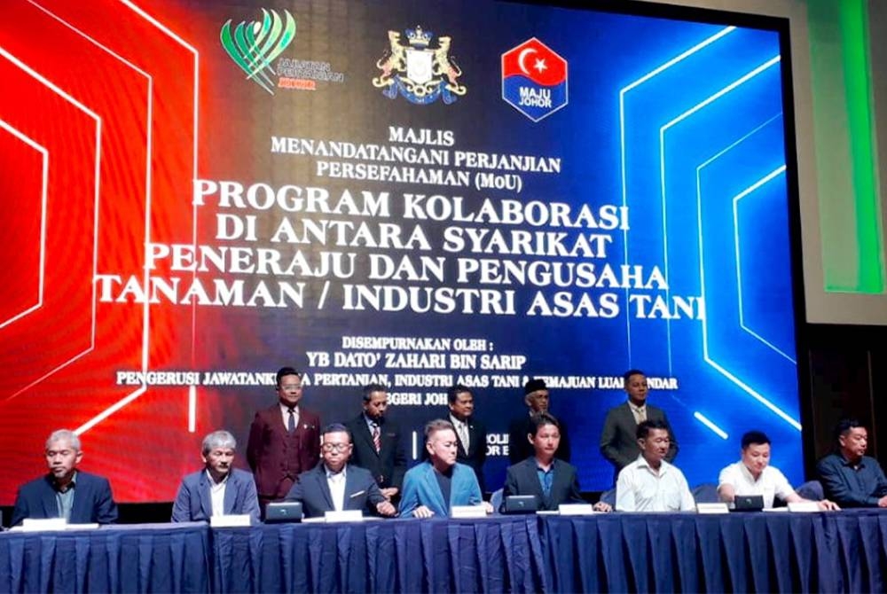 Zahari (tengah belakang) menyaksikan MoU dalam Program Kolaborasi di Antara Syarikat Peneraju dan Pengusaha Tanaman dan Industri Asas Tani yang diadakan di sebuah hotel di Johor Bahru pada Khamis.