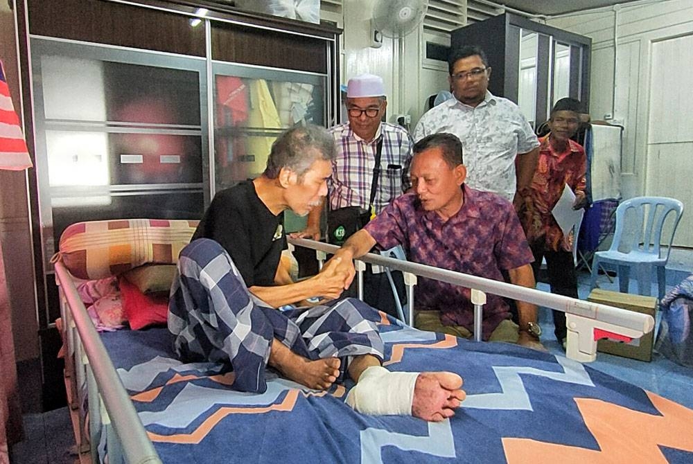 Roslan (kiri) ketika menerima kunjungan Zulkiflee (dua dari kiri) di rumahnya di Kampung Rantau Panjang pada Khamis.