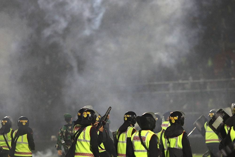 Anggota polis melepaskan gas pemedih mata semasa rusuhan selepas perlawanan bola sepak di Stadium Kanjuruhan di Malang, Jawa Timur, Indonesia pada Sabtu. - Foto EPA