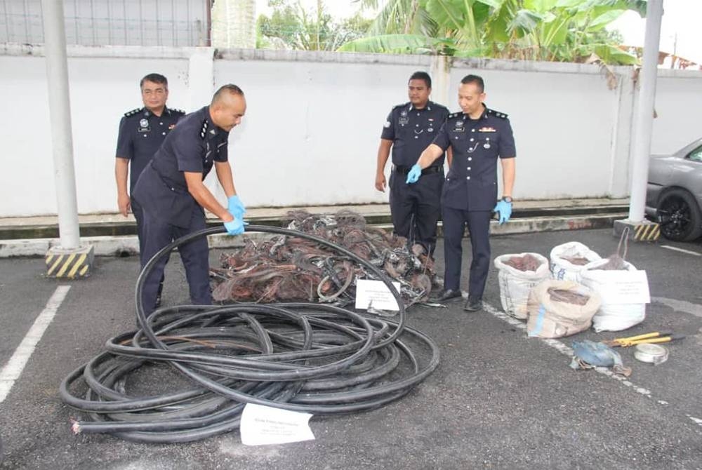 Ahmad Ridhwan (kanan) menunjukkan gulungan kabel yang dirampas polis.