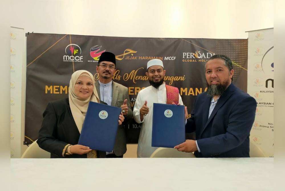 Mohd Hafizi (kanan) bertukar dokumen MoU bersama Marsita untuk Program Jejak Haramain MCCF.