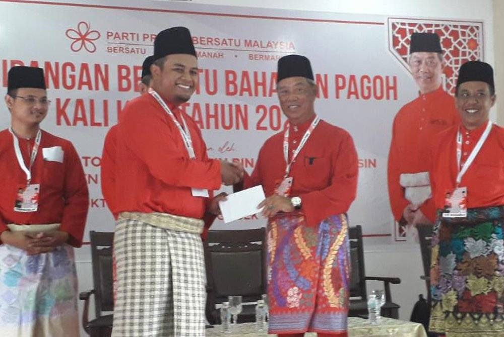 Muhyiddin (tengah) menyerahkan sumbangan untuk pembukaan Pusat Daerah Mengundi (PDM) pada Persidangan Bersatu Bahagian Pagoh di Dewan Geliga, pekan Gersik, Pagoh, Tangkak, pada Sabtu.