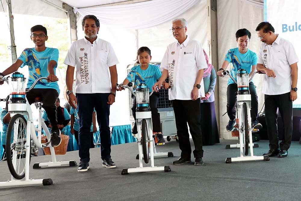 Ismail Sabri (empat dari kiri) dan Khairy (dua dari kiri) bersama remaja yang mengayuh basikal sempena kempen Malaysia Sejahtera. - Foto Bernama