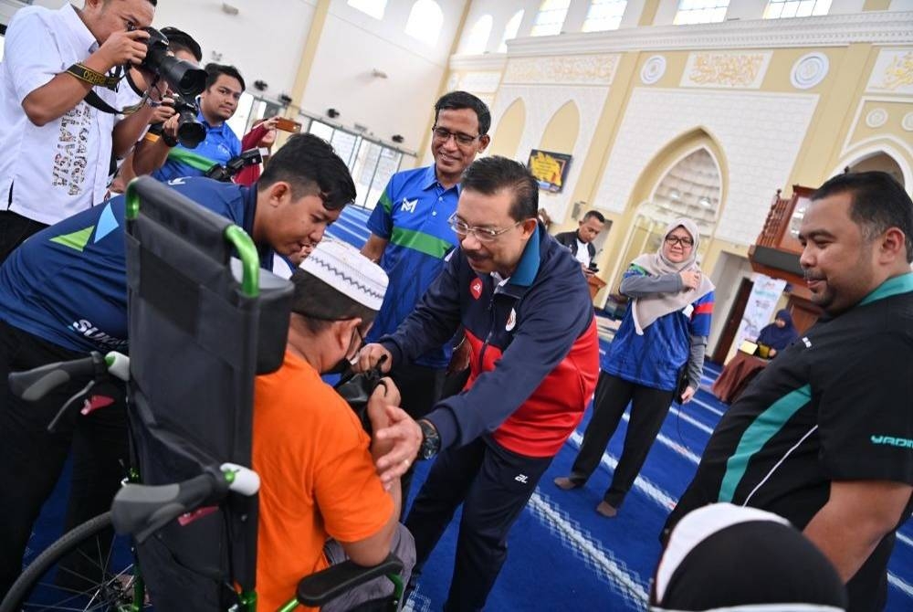 Mohd Zuki (dua dari kanan) menyampaikan sumbangan kepada salah seorang penerima di Masjid Tuanku Muhriz,Bandar Seri Jempol pada Sabtu.