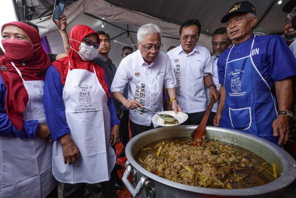 Ismail Sabri mencuba masakan daging lempap ketika hadir ke Kenduri Sekampung Keluarga Malaysia sempena Jelajah Aspirasi Keluarga Malaysia (AKM) di Felda Palong hari ini. - Foto Bernama