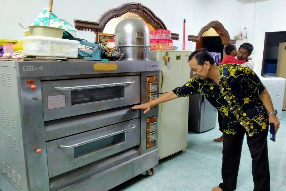 Mad Radzi menunjukkan paras air banjir yang merosakkan mesin ketuhar untuk membakar baulu ketika ditemui di rumahnya di RPT Chepor di sini pada malam Selasa.