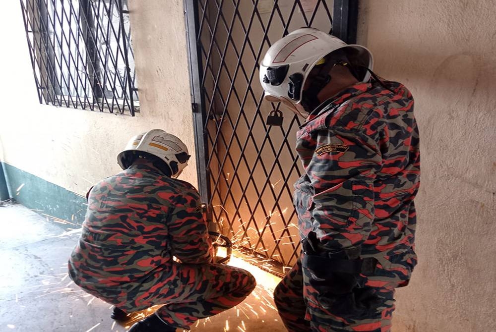 Pasukan bomba melakukan operasi membuka pintu jeriji yang berkunci di Flat Taman Sejati, Sandakan.