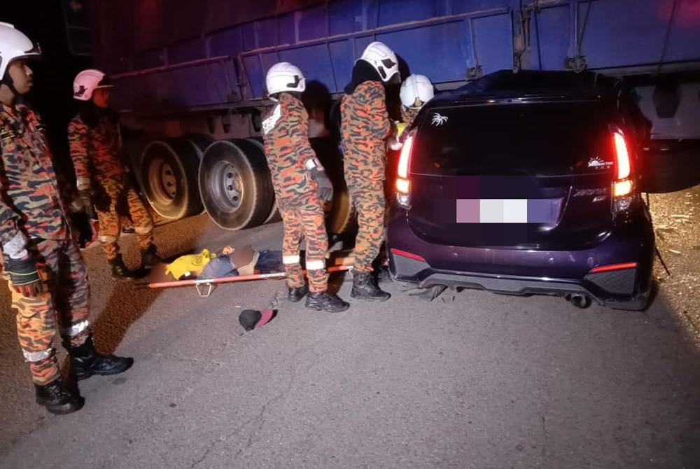 Anggota bomba membantu mengeluarkan mangsa yang tersepit dalam kenderaan selepas terbabit nahas dengan sebuah treler di Jalan Kuantan-Segamat dekat Pekan pada awal pagi Khamis. - Gambar ihsan JBPM Pahang